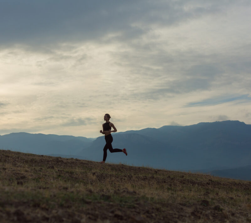 Silueta mlade žene koja trči u maglovitim planinama