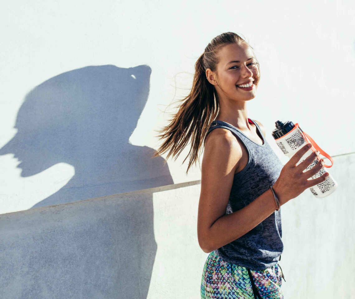 Žena drži bocu vode u odmoru od treninga